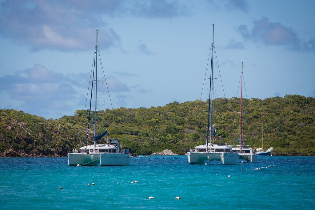 Charter catamarans lying to moorings off a low, scrub-covered cay