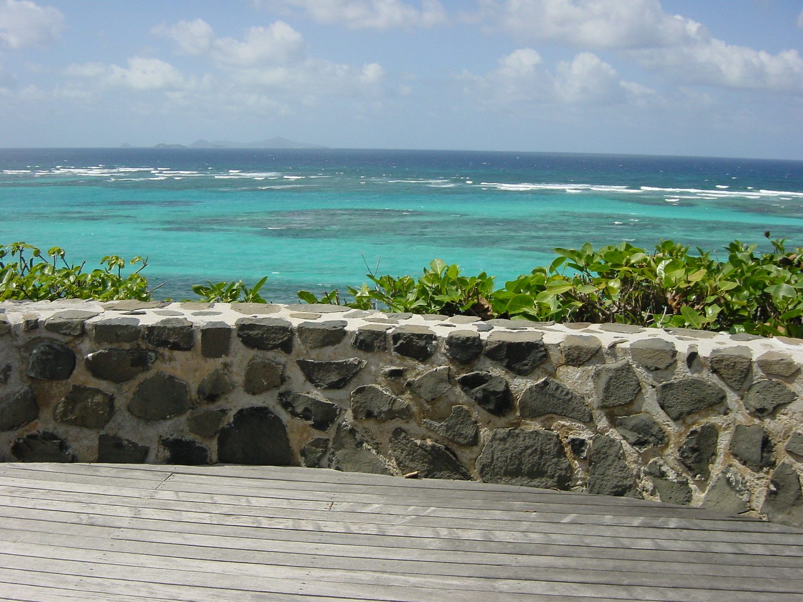A timber terrace above a turquoise lagoon, surf breaking on the reef beyond